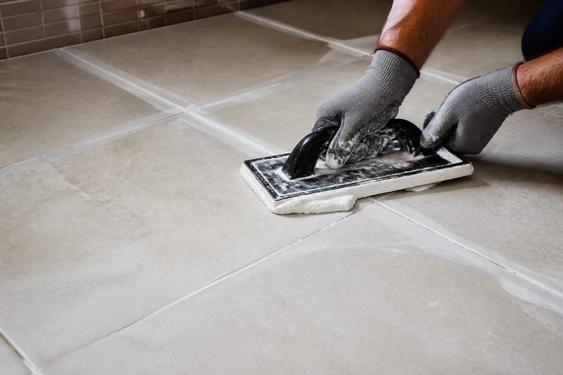 Hands applying grout between tiles